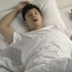 Young Asian man sleeping and snoring loudly lying in the bed